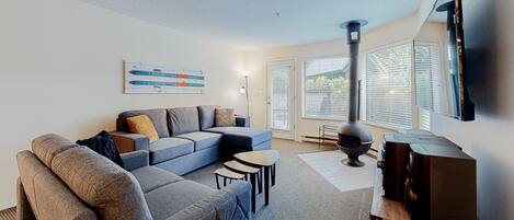A modern living room with a sectional sofa, a flat-screen TV, and a fireplace.