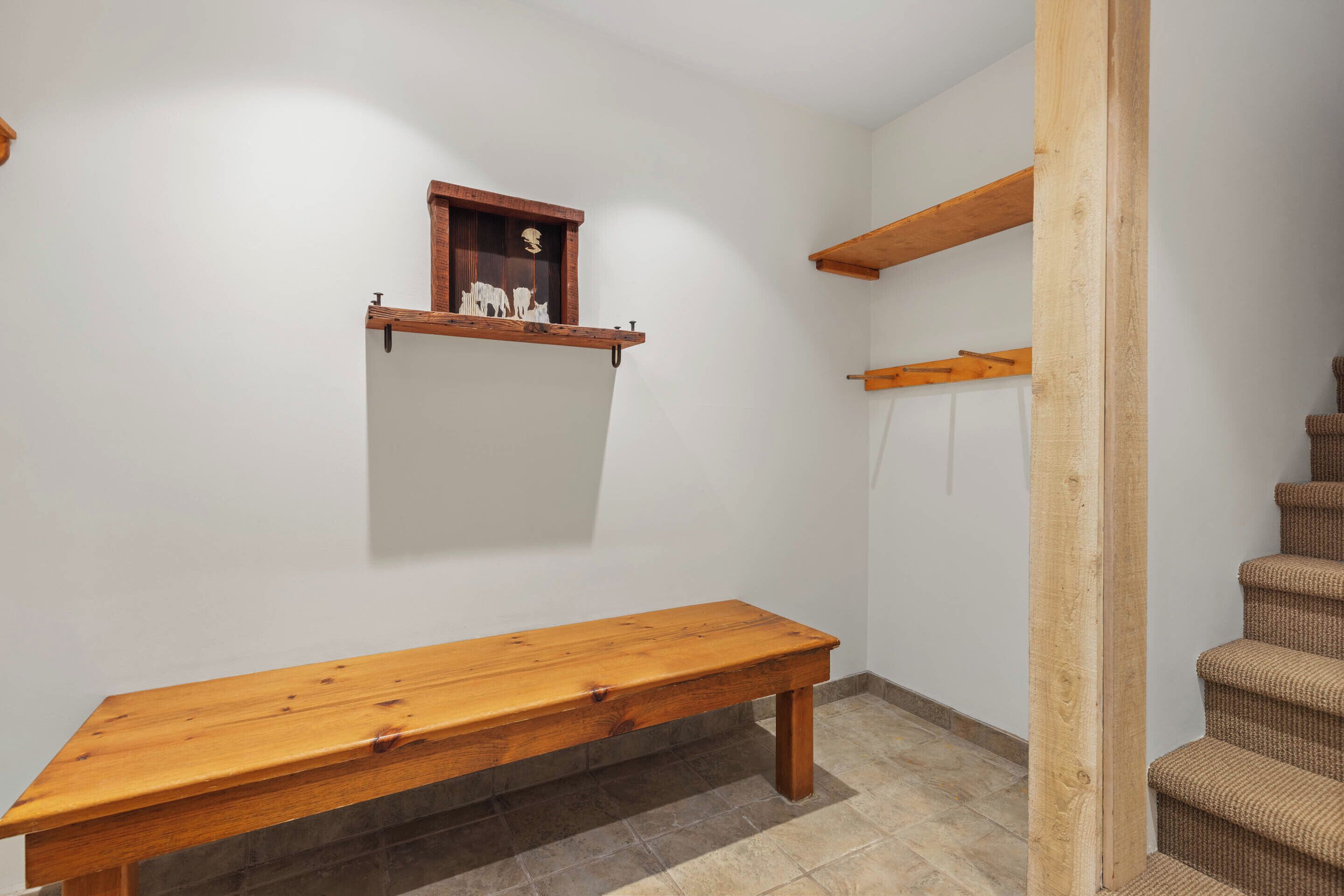 A wooden bench, a small wooden shelf with decorative items, and a staircase.
