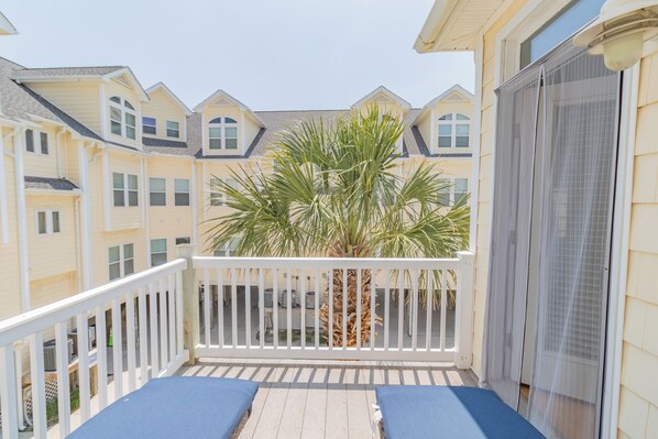 A balcony with a white railing, a palm tree, and a view of neighboring buildings. - New Listing | 0.1 Miles to Beach| Pool Access (Surf City)