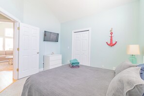 A bedroom with a bed, a TV mounted on the wall, a door, and a wall-mounted anchor decoration. - New Listing | 0.1 Miles to Beach| Pool Access (Surf City)