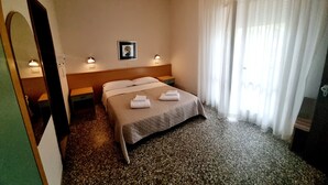A hotel room with a bed, two bedside tables, a mirror, a picture on the wall, and a window with curtains. - hotel Anny  (Cervia)