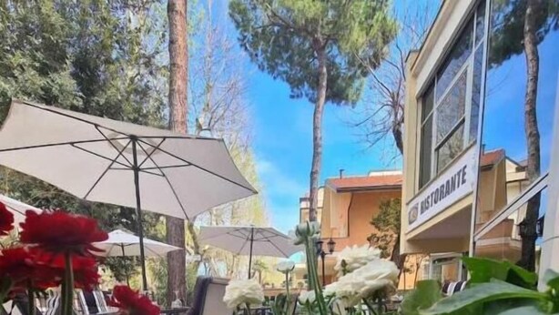 An outdoor seating area with tables and chairs, surrounded by greenery and flowers. - hotel Anny  (Cervia)