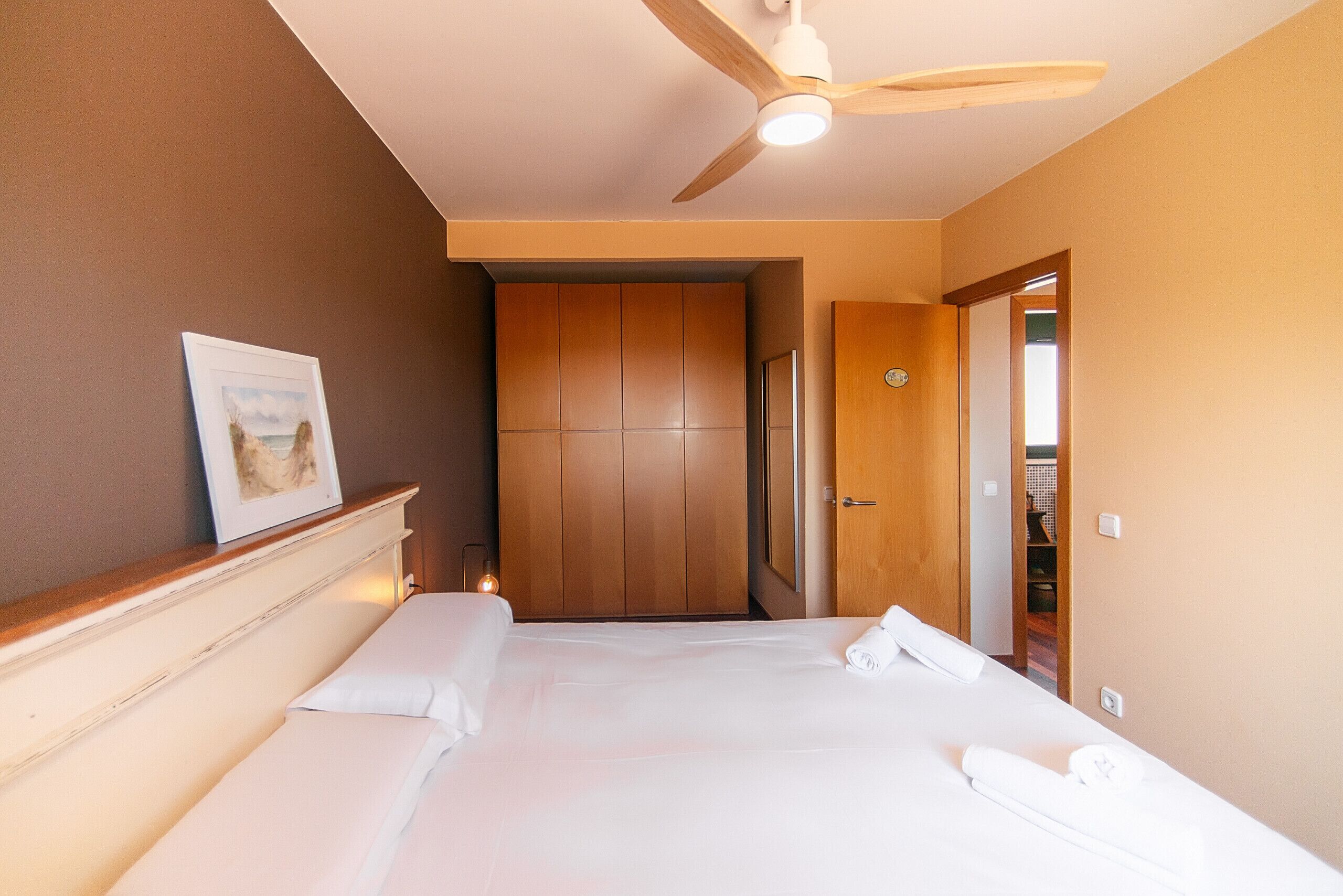 Hotelkamer met een bed, een plafondventilator, een inlijsting foto aan de muur en een deur naar een kast.
