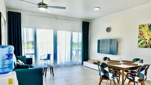 Ein modernes Wohnzimmer mit einer Couch, einem Esstisch mit Stühlen, einem Fernseher und einem Wasserspender.
