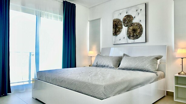 Ein modernes Schlafzimmer mit einem großen Bett, einem Deckenventilator und einem Wandbild.