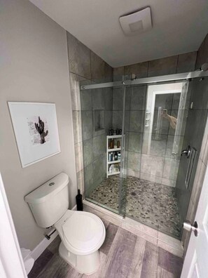 Une salle de bain moderne avec des toilettes, une douche et une porte en verre.