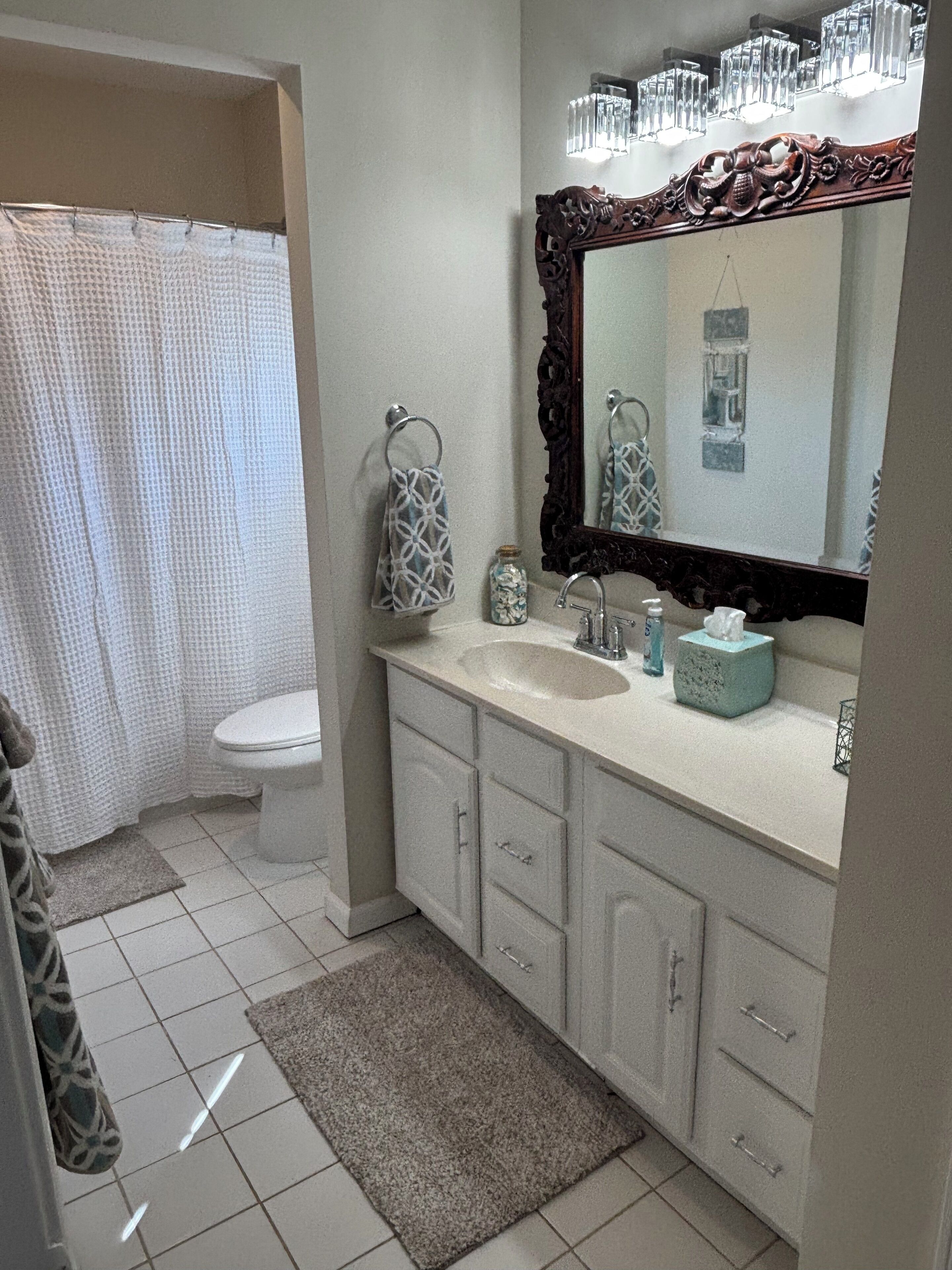 A bathroom with a white toilet, a sink with a mirror above it, and a shower curtain.