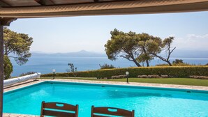 A swimming pool with two wooden chairs, a pergola overhead, and a view of the sea and mountains. - Lahtagas Estate with private swimming pool (Loutraki)