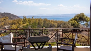 A balcony with a table and chairs, overlooking a scenic view of a body of water and hills. - Lahtagas Estate with private swimming pool (Loutraki)