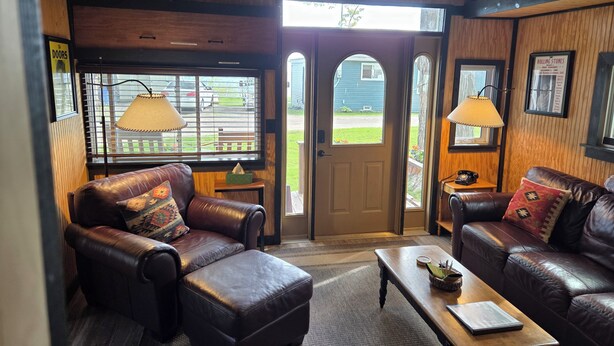 A cozy interior with leather sofas, a wooden ceiling, and a view through a door. - "That 70's Cottage" (on Lake Erie!) Free Firewood! (Essex)