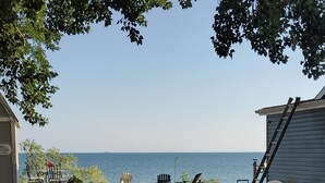 A gravel area with a beach view, outdoor seating, and a small building. - "That 70's Cottage" (on Lake Erie!) Free Firewood! (Essex)