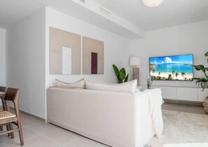 A modern living room with a sofa, a television, and a view of the ocean.