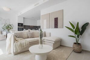 Ein modernes Wohnzimmer mit einer Couch, einem Couchtisch und einer Topfpflanze.