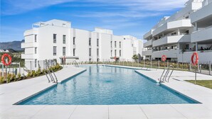 A modern building with a swimming pool surrounded by a white fence and lifebuoys.