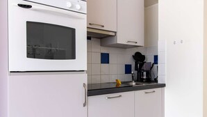 Une cuisine avec des meubles blancs, un plan de travail noir et une machine à café.