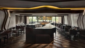 A modern bar area with a central island, seating arrangements, and a view of the outdoors. - Ramada Encore By Wyndham Ambala Gt Road (Ambala)