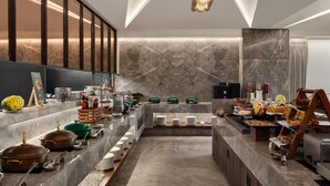 A modern buffet setup with various food items and utensils. - Ramada Encore By Wyndham Ambala Gt Road (Ambala)