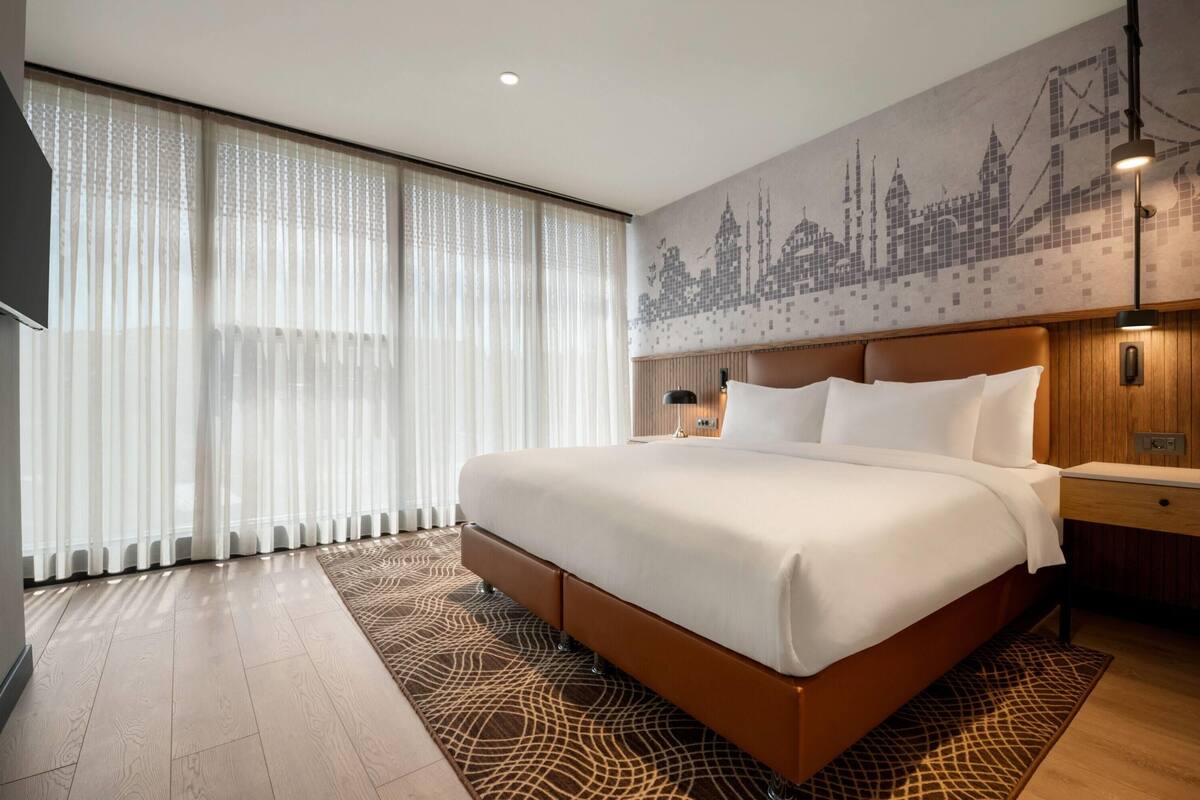 A large bed with a wooden headboard, a bedside table, and a wall-mounted TV.