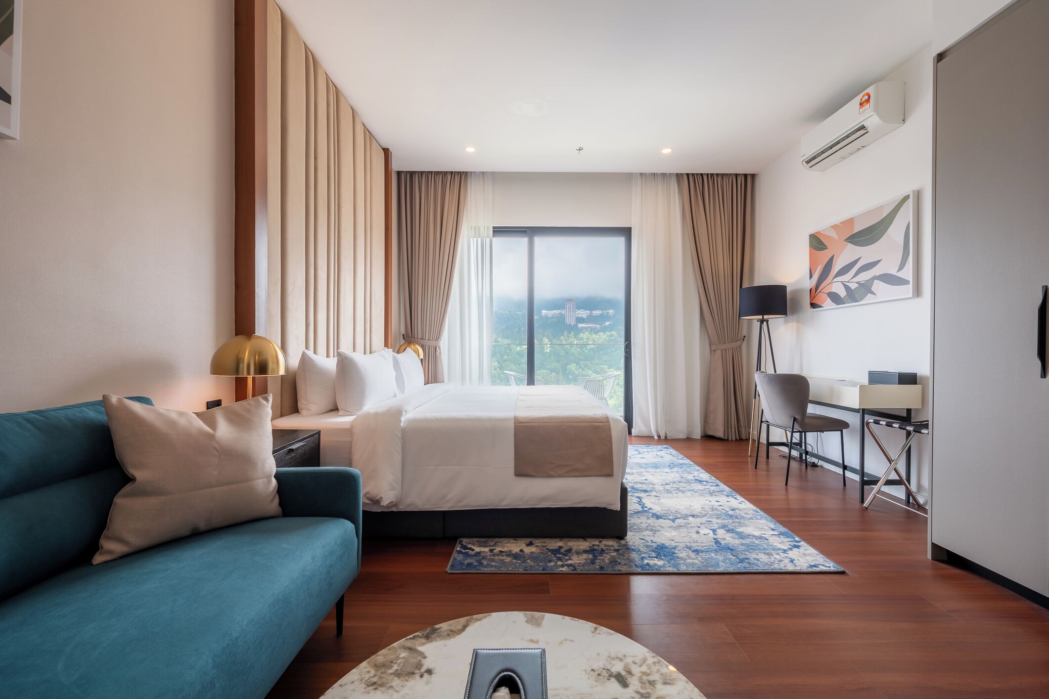 A modern hotel room with a large bed, a desk, a sofa, and a view of the city.