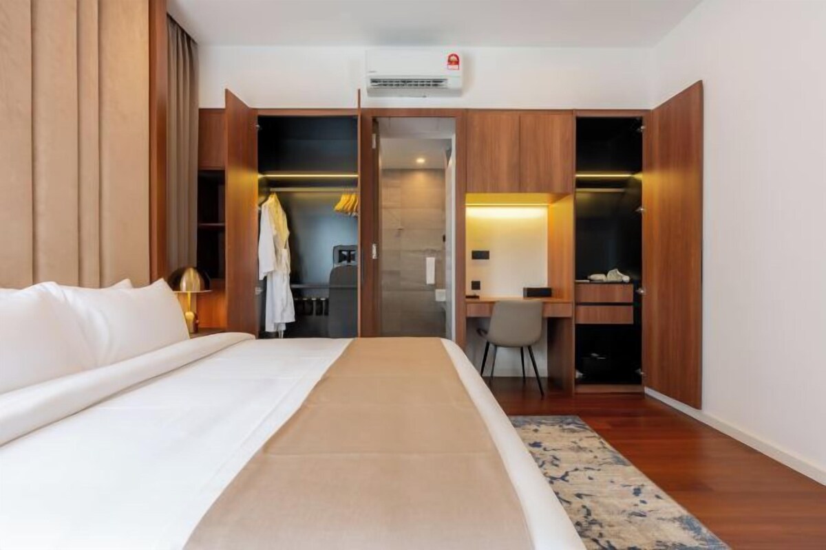A hotel room with a bed, a desk, a chair, a wardrobe, and a bathroom.