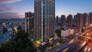 A high-rise building with a modern design, surrounded by other high-rise buildings and a busy road with moving vehicles. - Days Hotel By Wyndham Zhuzhou Shifeng (Zhuzhou)