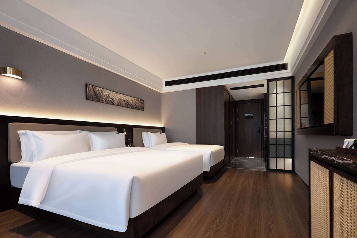 Ein Hotelzimmer mit zwei Betten, einem großen Spiegel und einem Holzboden.
