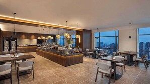 A modern hotel lobby with a central island, seating arrangements, and large windows offering a city view. - Days Hotel By Wyndham Zhuzhou Shifeng (Zhuzhou)