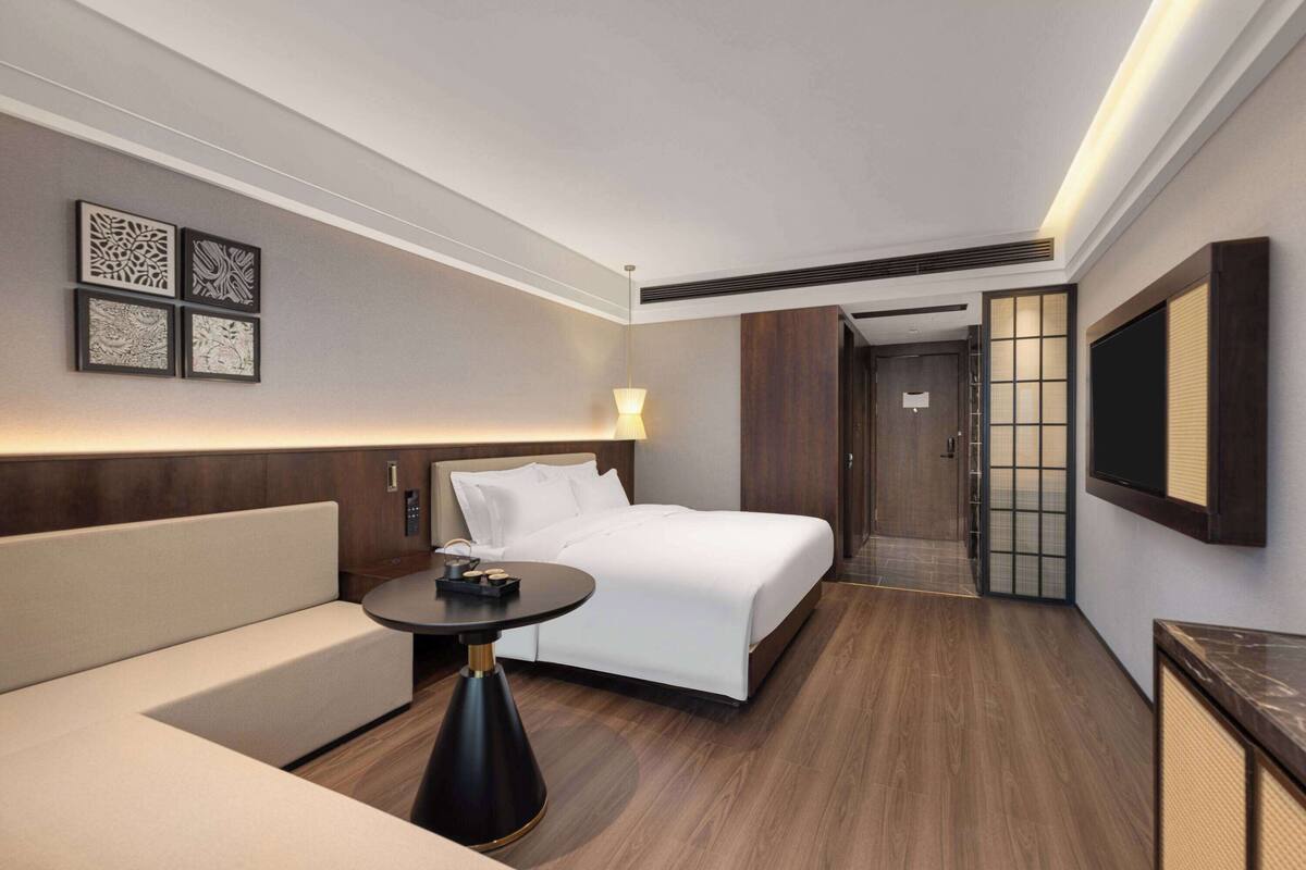 Ein Hotelzimmer mit Bett, Sofa, Tisch und Fernseher.