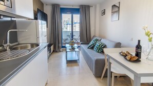 Un espacio habitable compacto con kitchenette, comedor y sofá con vistas al exterior.