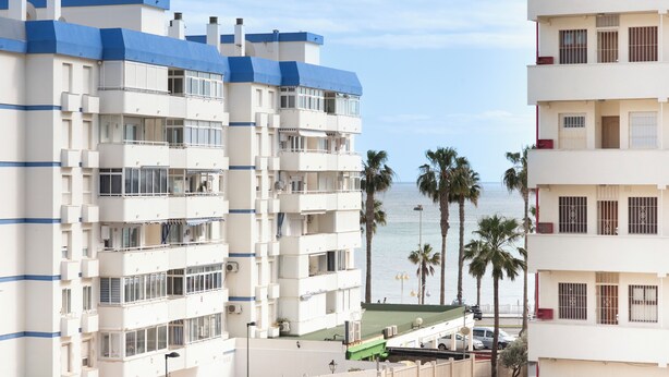 Un hotel de varios pisos con balcones, zona de piscina y vistas a la playa y el océano.