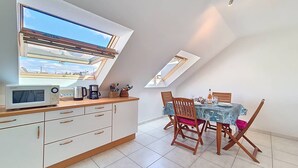 Eine Küche mit Dachfenster, einem Essbereich mit Tisch und Stühlen sowie einer Mikrowelle auf der Arbeitsfläche.