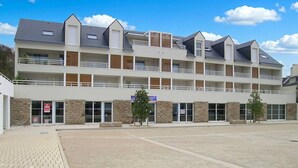 Ein mehrstöckiges Hotel mit Balkonen, einem Parkplatz und einer Ziegel-Fassade.