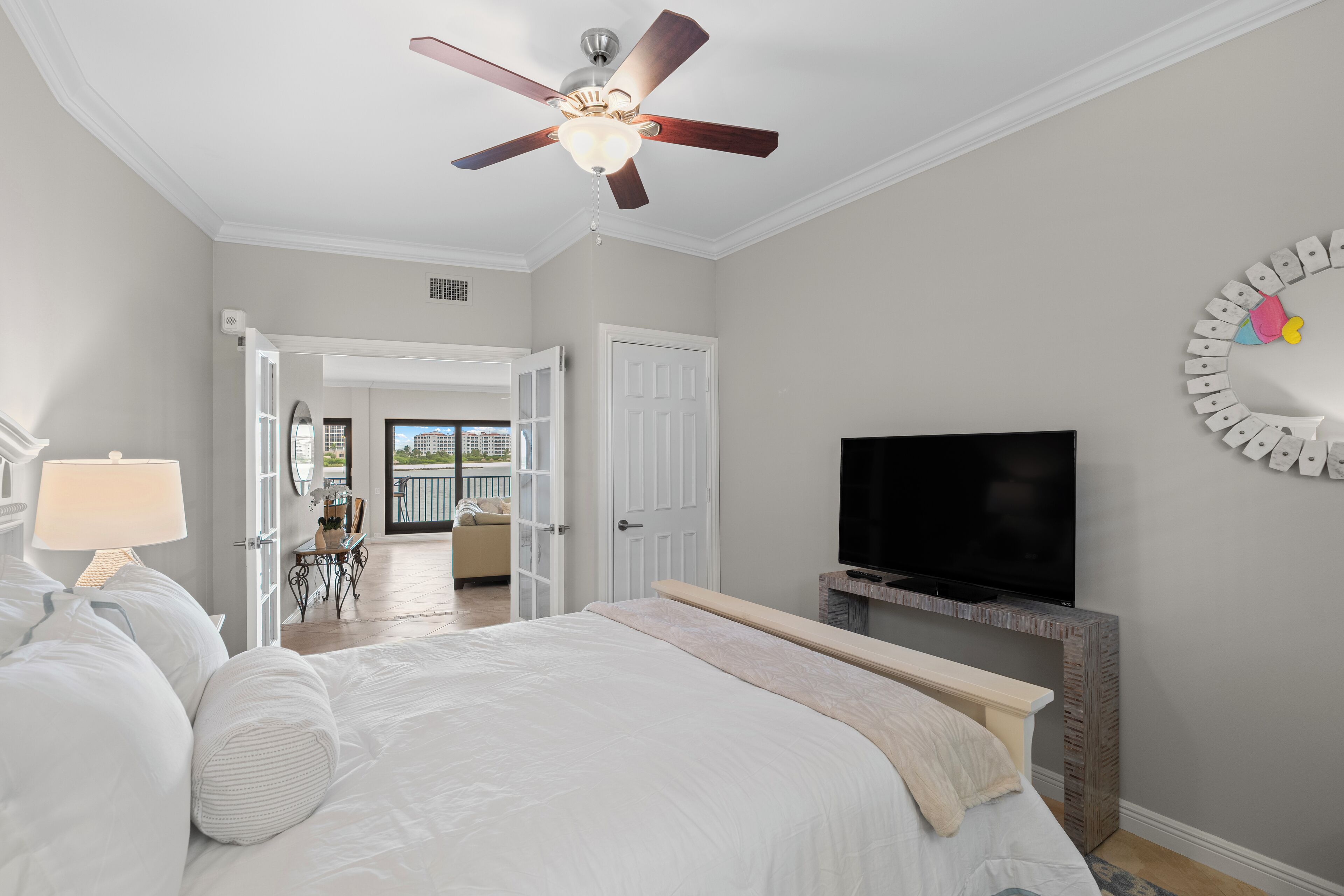 Quarto com cama, ventilador de teto, televisão e vista para o exterior.