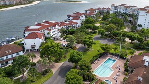 A resort with multiple white buildings, a swimming pool, and a view of the ocean.