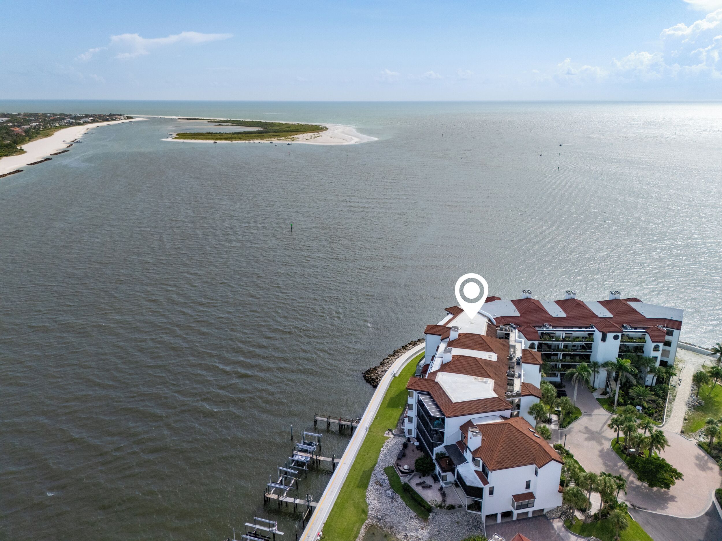 A coastal hotel with multiple buildings, a dock, and a view of the ocean.