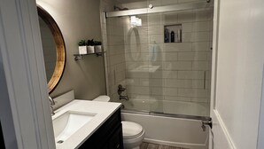 Une salle de bain moderne avec une douche à parois de verre, un meuble-lavabo à deux vasques et des toilettes.
