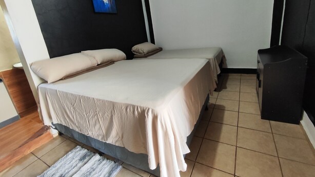 Ein Schlafzimmer mit einem Bett, Kissen, einem Bild an der Wand und einem kleinen schwarzen Schrank.