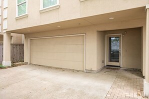 A residential building with a garage, a wooden fence, and a paved driveway. - 30% Off - 3 Bed Townhome- Oak Lawn - Pet Friendly (Dallas)