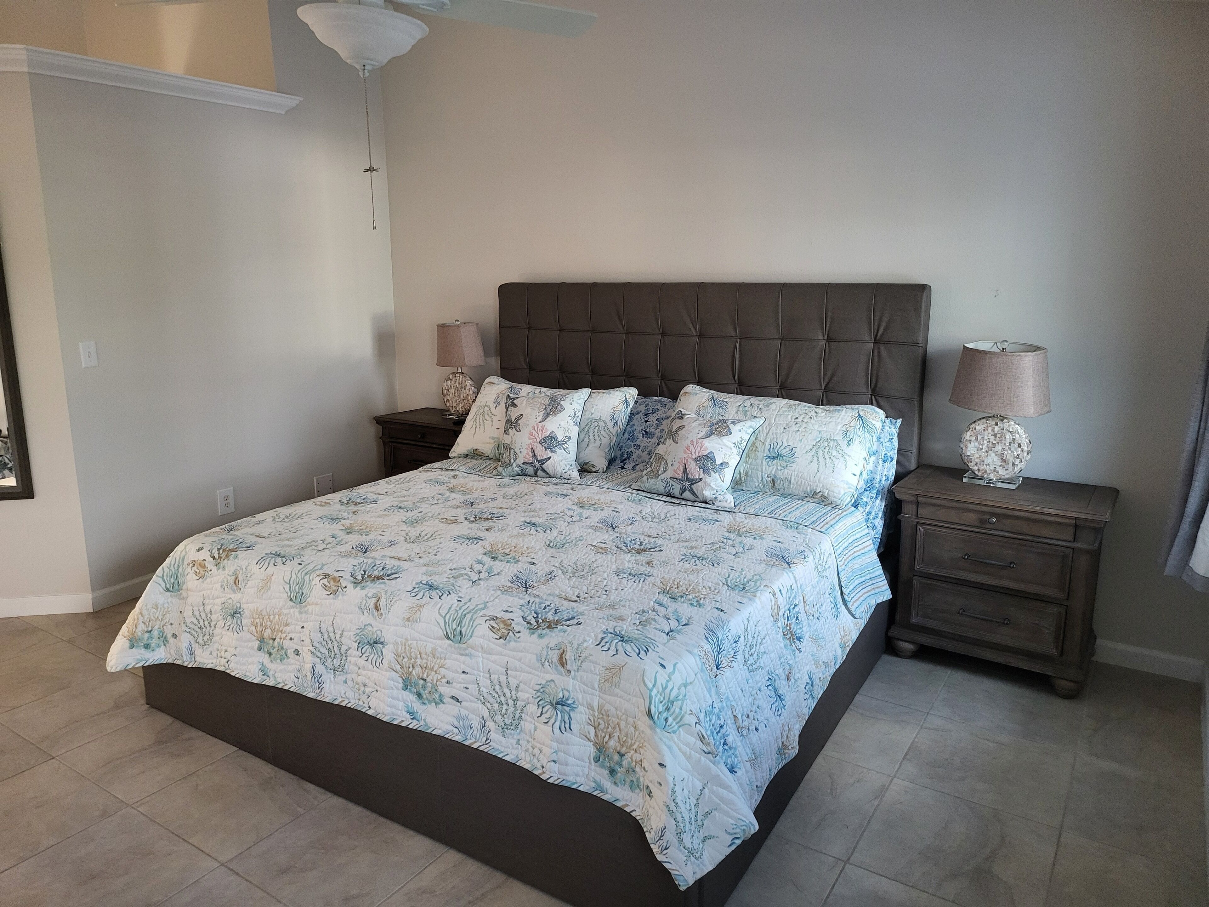 A bedroom with a bed, nightstands, a lamp, and a ceiling fan.