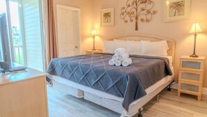 Een slaapkamer met een bed, een bureau, een lamp en een wanddecoratie.