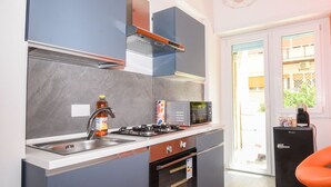Una cocina compacta con estufa a gas, horno, microondas y un refrigerador pequeño.