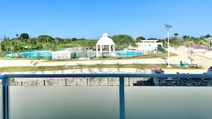 Ein Poolbereich mit einem weißen Gazebo, umgeben von Grünpflanzen und blauem Himmel.