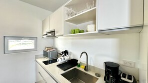 Una cocina moderna con un lavamanos de acero inoxidable, una cafetera y un microondas.