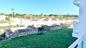 Blick auf eine angelegte Grünfläche mit einer Steinmauer, Gras und blühenden Pflanzen.