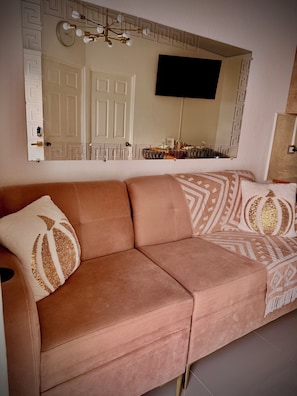A living room with a sofa, a television, and a decorative mirror.