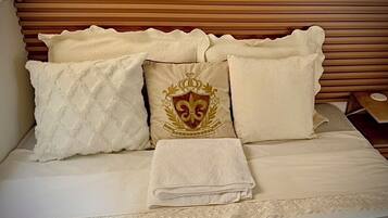 Un lit avec une tête de lit, des oreillers et une serviette pliée.