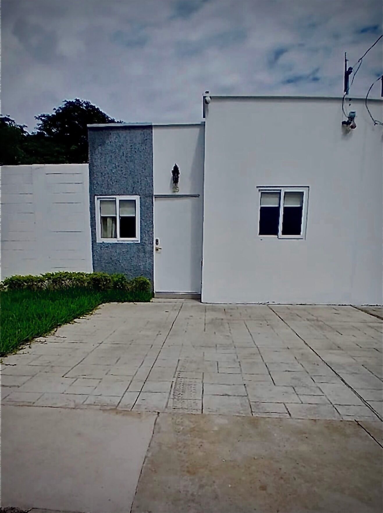 A modern building with a flat roof, a small window, and a door.