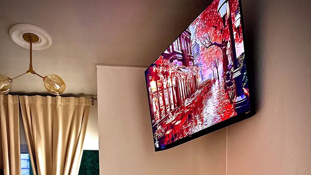 Ruokailutila, jossa on kahdelle katettu pöytä, seinälle asennettu televisio ja näkymä ulos ikkunasta.