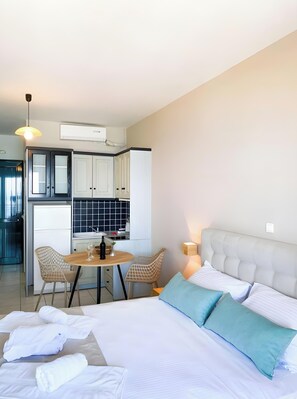 Una habitación de hotel con cama, una mesa de comedor con sillas, una zona de cocina y un baño.