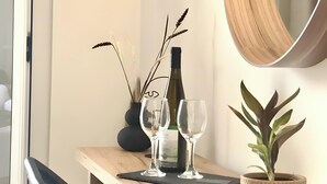 A wooden dining table with two wine glasses, a bottle, and a potted plant.